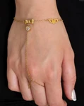 Gold hand chain bracelet featuring a delicate chain connecting a wrist bracelet to a finger ring, accented with small butterfly charms, worn on a hand.
